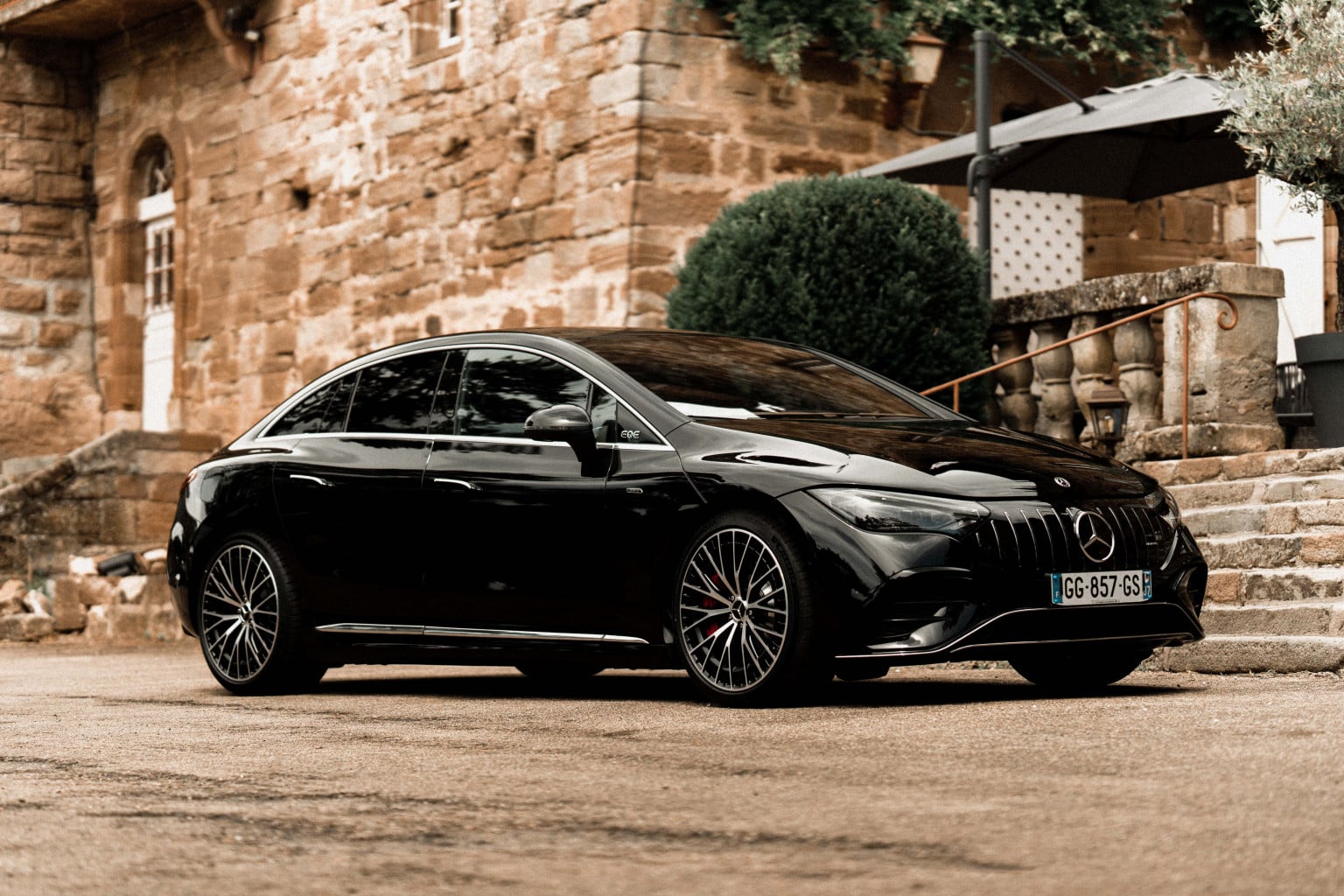 Berline électrique Mercedes-AMG noire garée devant une bâtisse en pierre