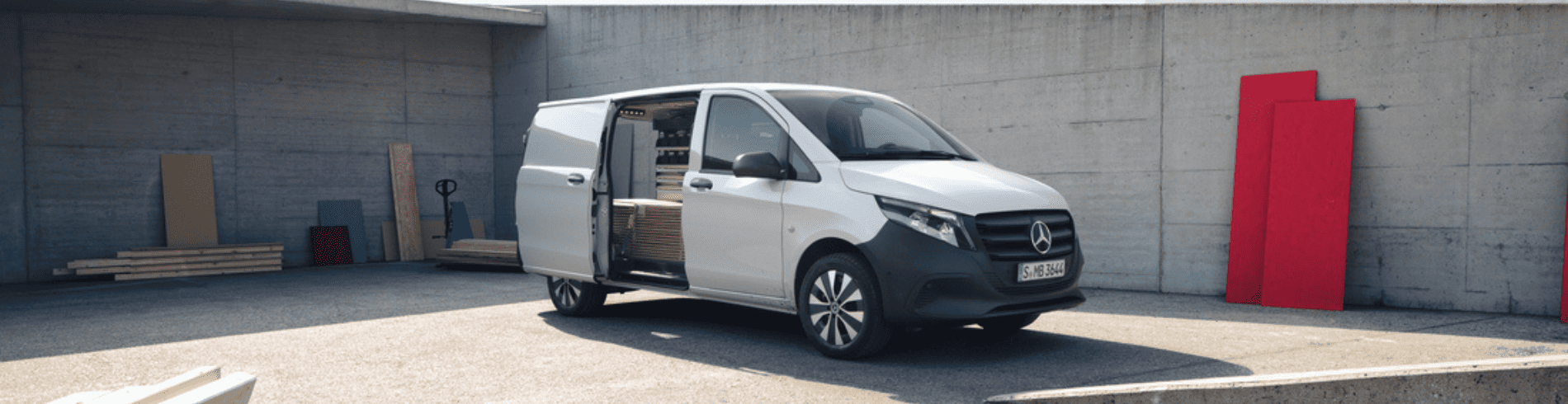 Mercedes-Benz Vito argenté avec porte latérale ouverte devant un mur en béton