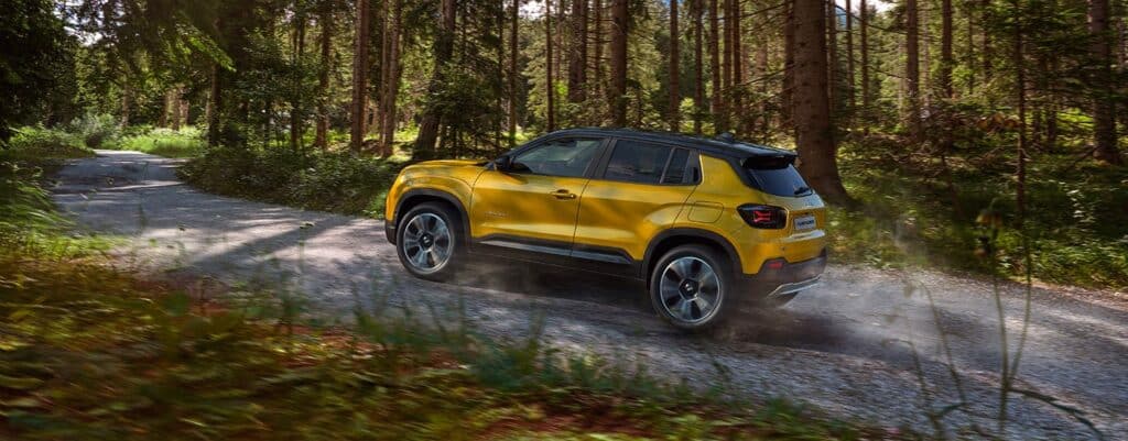 Jeep Avenger jaune roulant sur une piste forestière